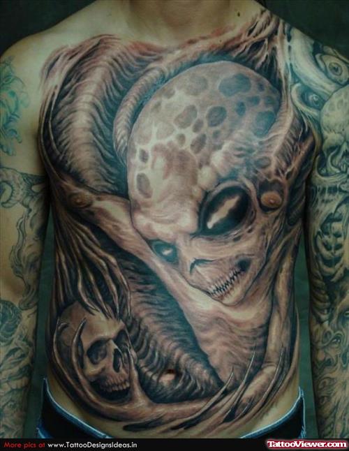 Grey Ink Alien Head And Skull Tattoo On Chest