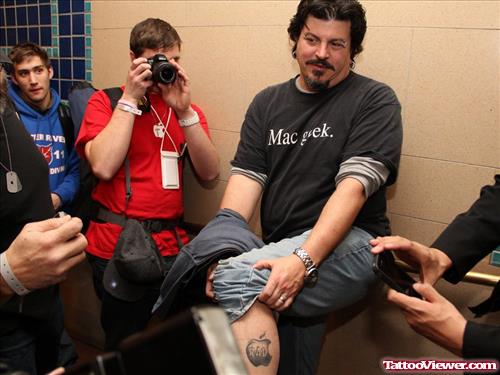 Man Showing Grey Apple Tattoo On Left Leg
