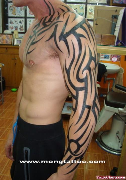 Black Ink Tribal Tattoo On Man Chest And Left Arm