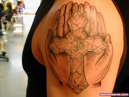 Grey Ink Cross In Hands Tattoo On Left Arm