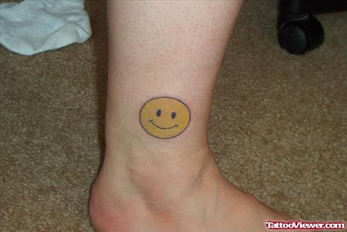 Yellow Ink Smiley Face Tattoo On Leg