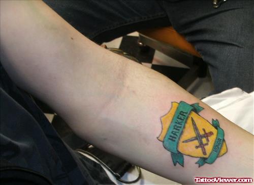 Yellow And Green Ink Family Crest Tattoo On Left Forearm