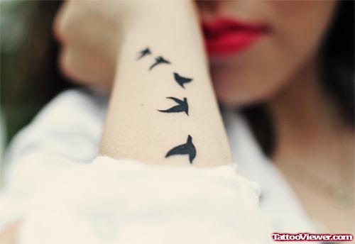 Black Ink Flying Birds Feminine Tattoo On Arm
