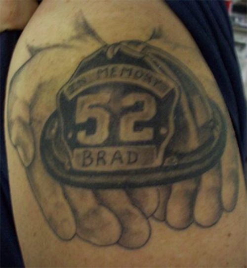 Grey Ink Firefighter Hat In Hands Tattoo On Shoulder