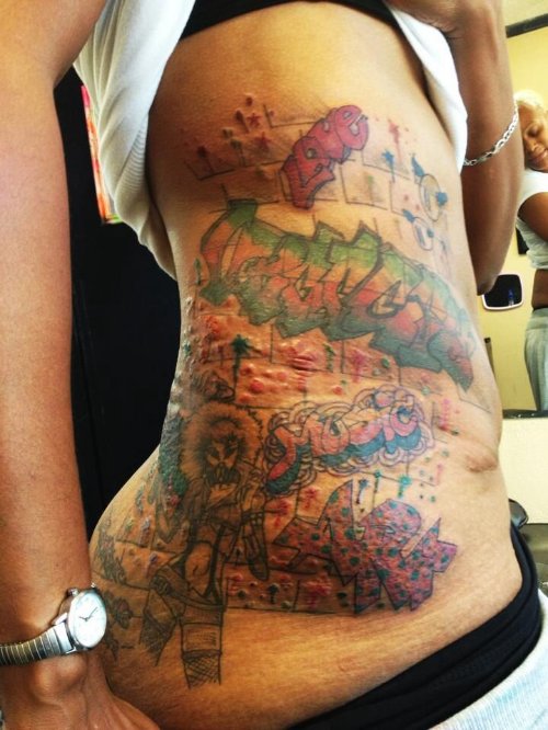 Girl Showing Graffiti Tattoo On Side Rib