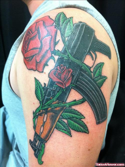 Red Roses And Gun Tattoo On Man Left Shoulder