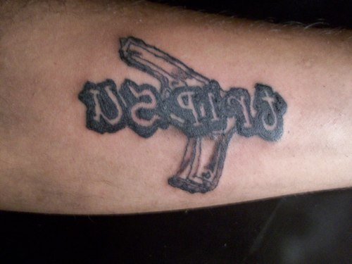 Grey Ink Word And Gun Tattoo