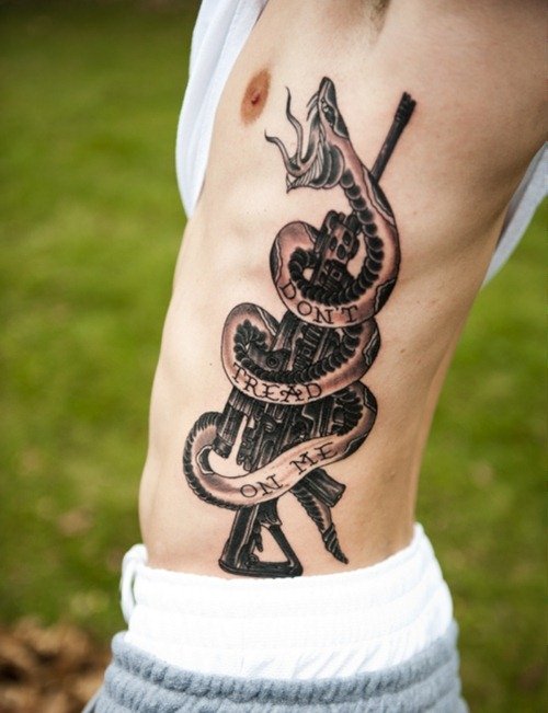 Grey Ink Snake and Gun Tattoo On Man Side Rib