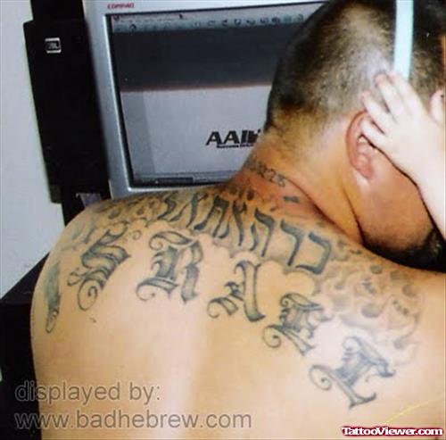 Grey Ink Hebrew Tattoo On Man Upperback