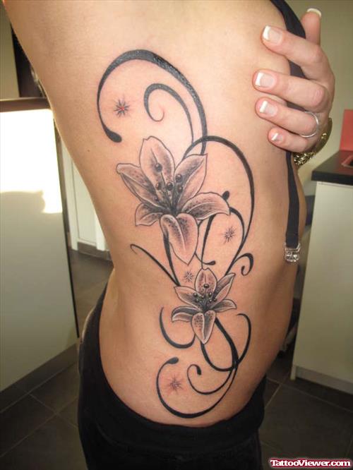 Grey Ink Tribal And Flowers Tattoo On Side Rib
