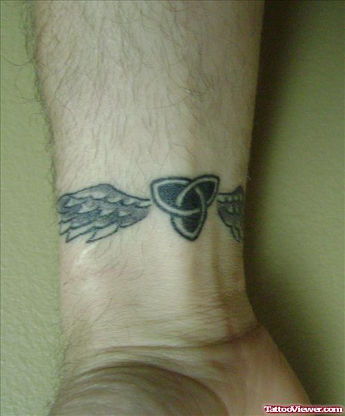 Grey Ink Winged Celtic Knot Tattoo On Wrist