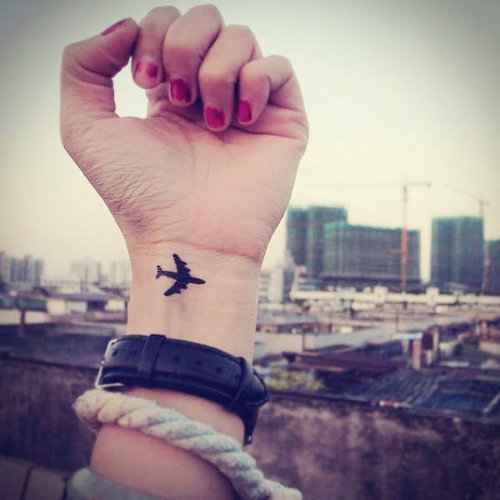 Small Black Airplane Tattoo On Girl Left Wrist