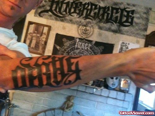 Black Ink Ambigram Tattoo On Left Arm