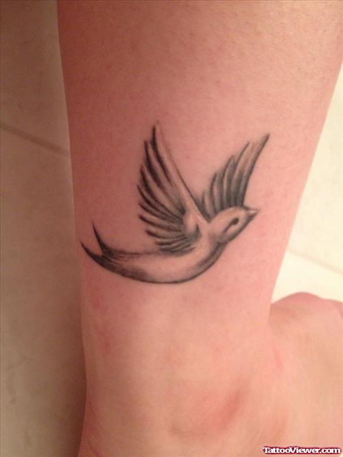 Grey Ink Flying Bird Ankle Tattoo