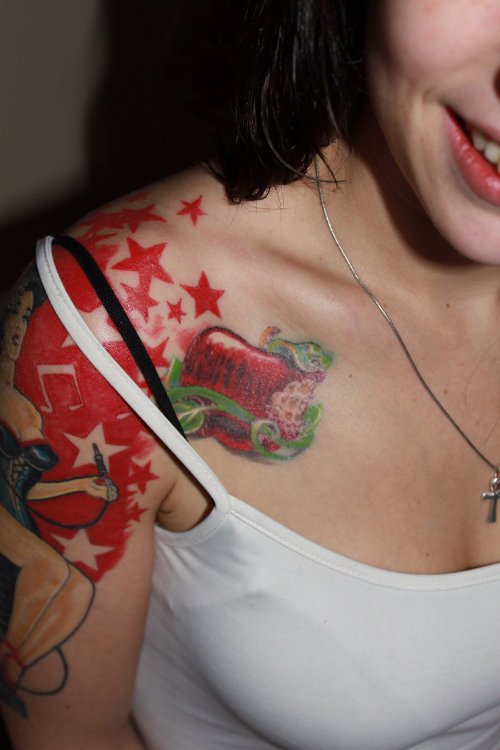 Red Ink Apple Tattoo On Girl Right Shoulder