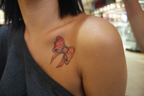 Pink Bow Tattoo On Collarbone