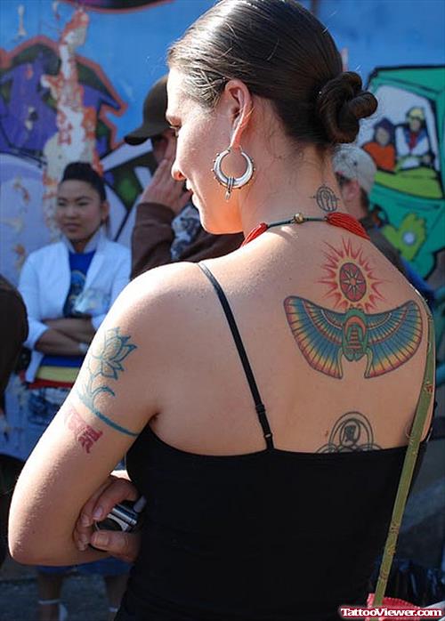 Woman With Sun And Egyptian Tattoo On Upperback