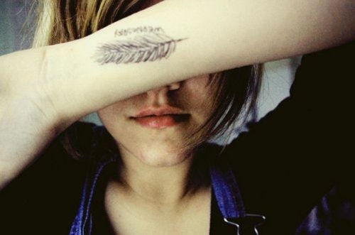 Girl With Grey Ink Feather Tattoo On Left Wrist