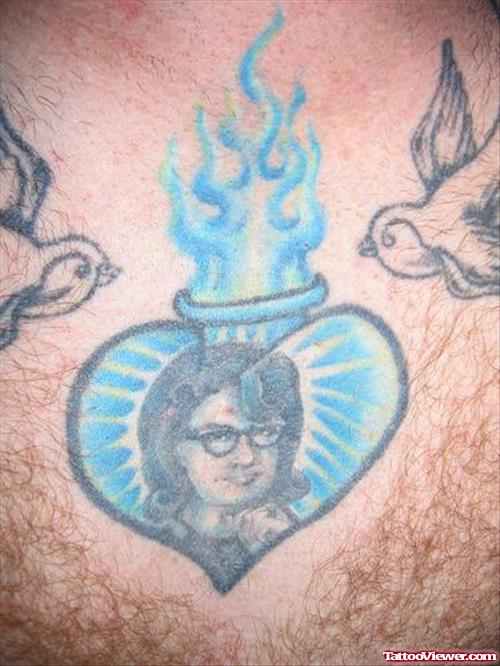 Blue Ink Flaming Heart Tattoo On Chest