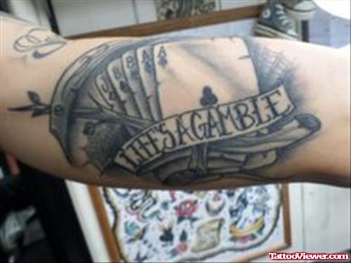 Grey Ink Cards And Gamble Banner Tattoo On Arm