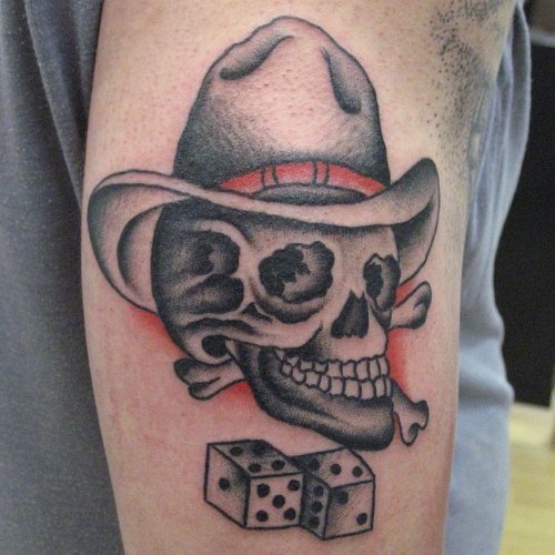 Grey Ink Skull With Hat And Dice Gambling Tattoo On Bicep