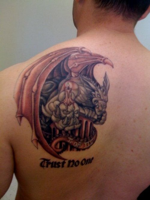 Gargoyle With Candle And Trust No One Text Tattoo On Back Shoulder