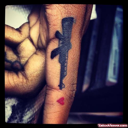 Black Ink Gun And Tiny Heart Tattoo On Finger