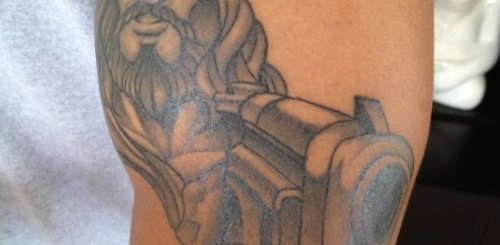 Grey Ink Jesus With Gun Tattoo On Bicep
