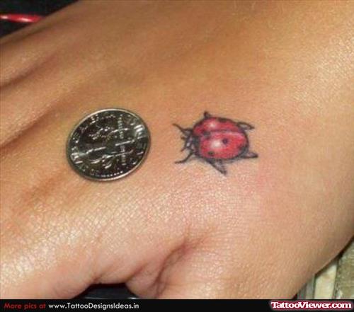 Red Ink Small Ladybug Tattoo On Hand