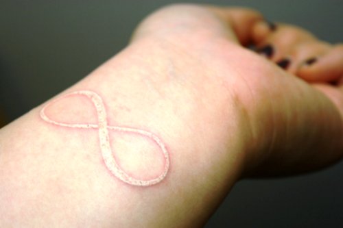 White Ink Infinity Tattoo On Left Wrist