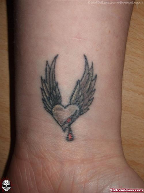 Grey Ink Winged Heart Tattoo On Wrist